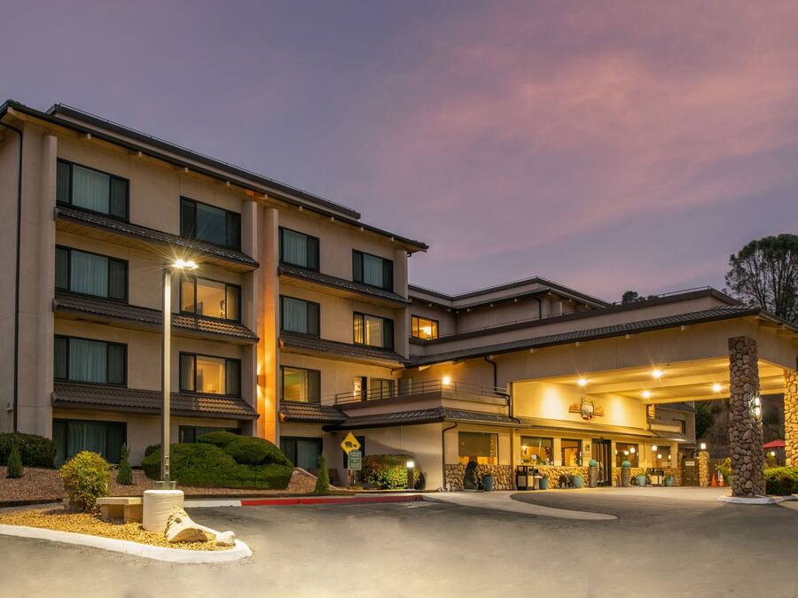 A multi-story hotel with a well-lit entrance and a landscaped driveway.