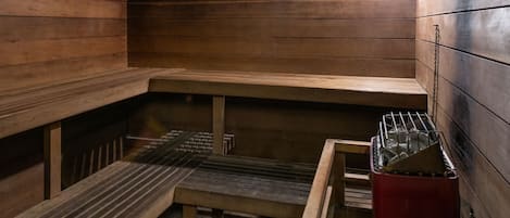 A sauna with wooden benches and a bench with a metal frame.