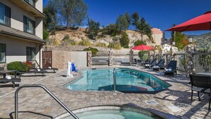 Un área de piscina con jacuzzi, sillas de descanso y sombrillas.