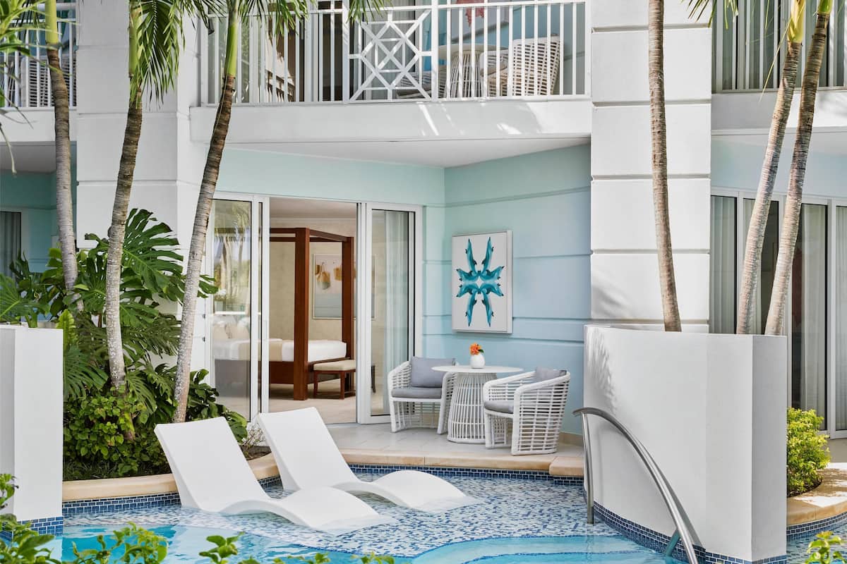 A poolside area with lounge chairs, a small table, and a bed in a room with a view.