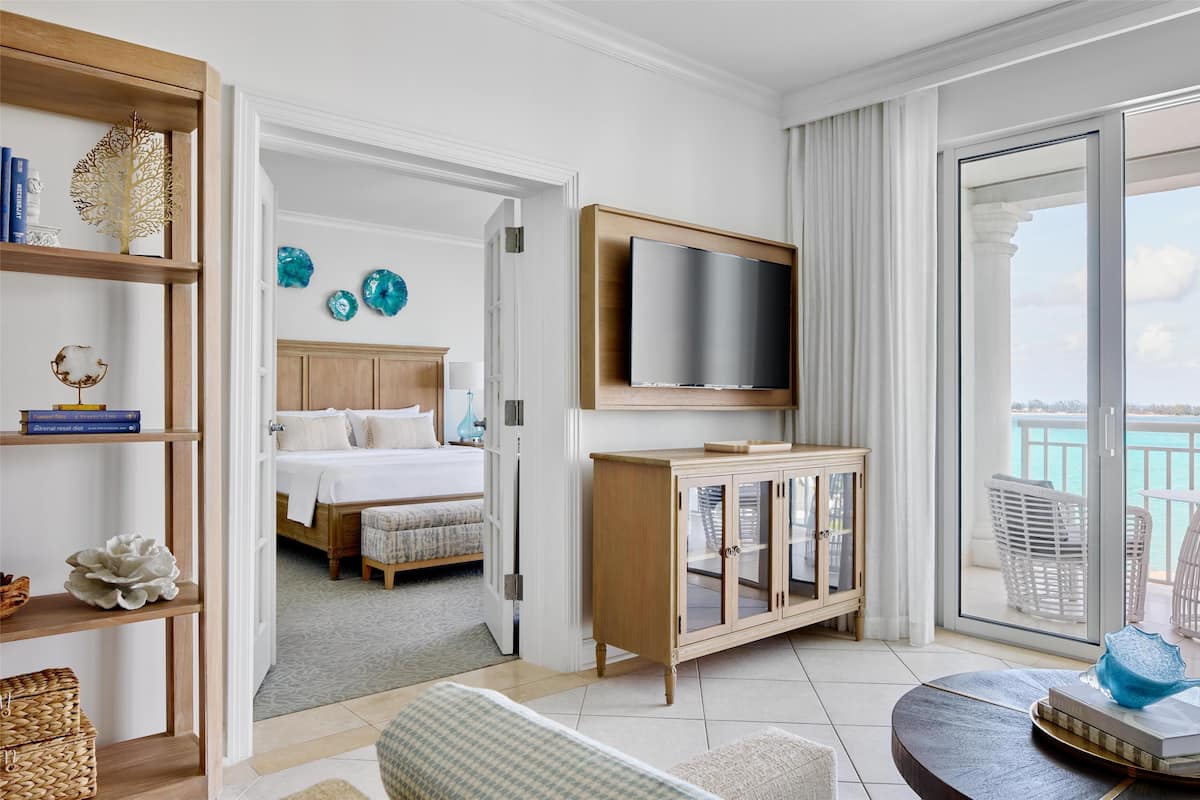 A hotel room with a bed, a TV, a wooden cabinet, and a balcony with a view.