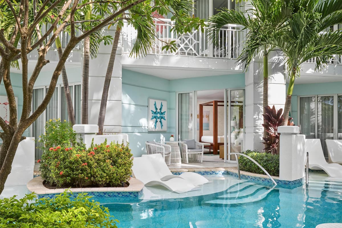 A pool area with lounge chairs, a small pool, and a balcony with white railings.
