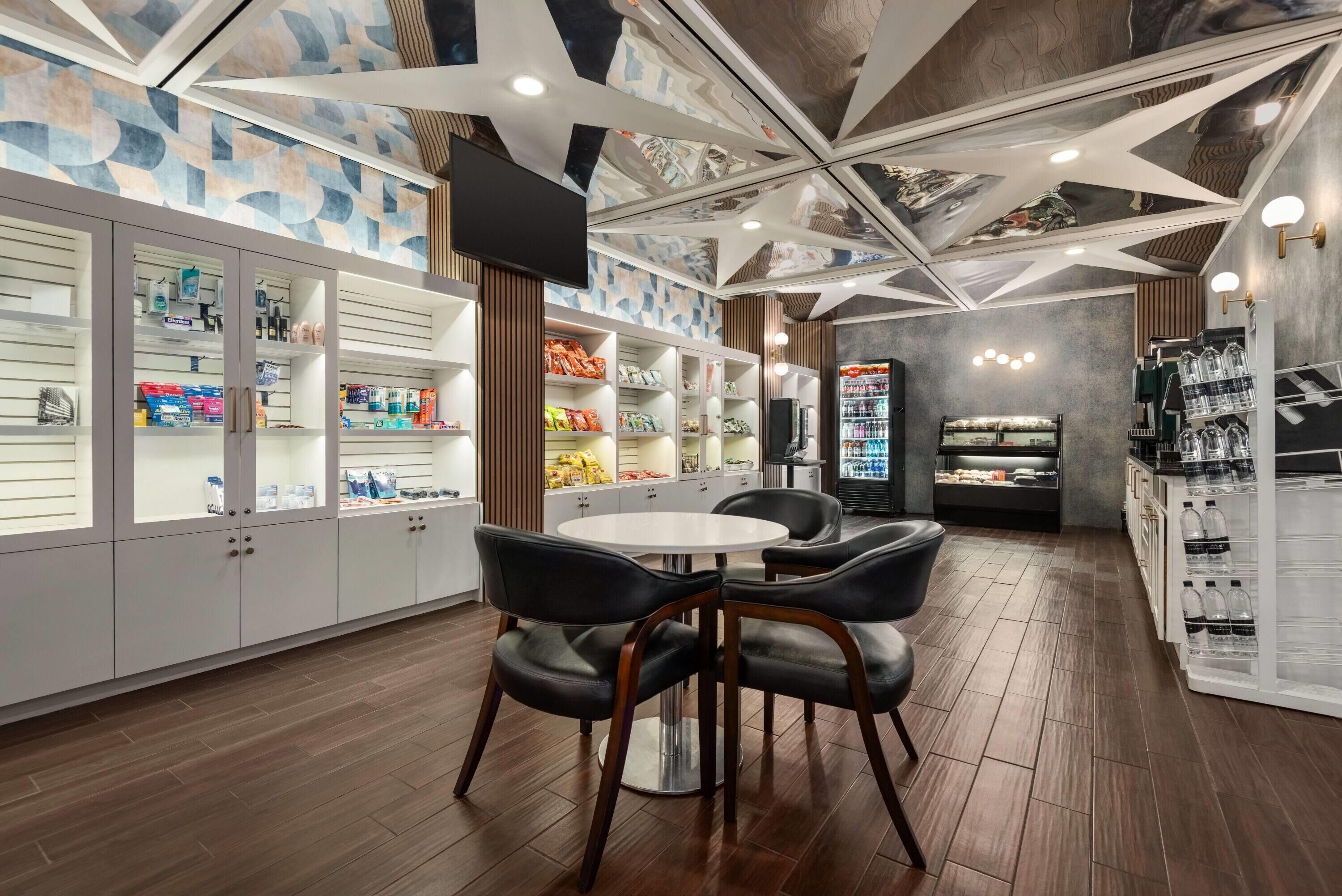 A modern interior with a round dining table and chairs, a display of snacks, and a beverage refrigerator.