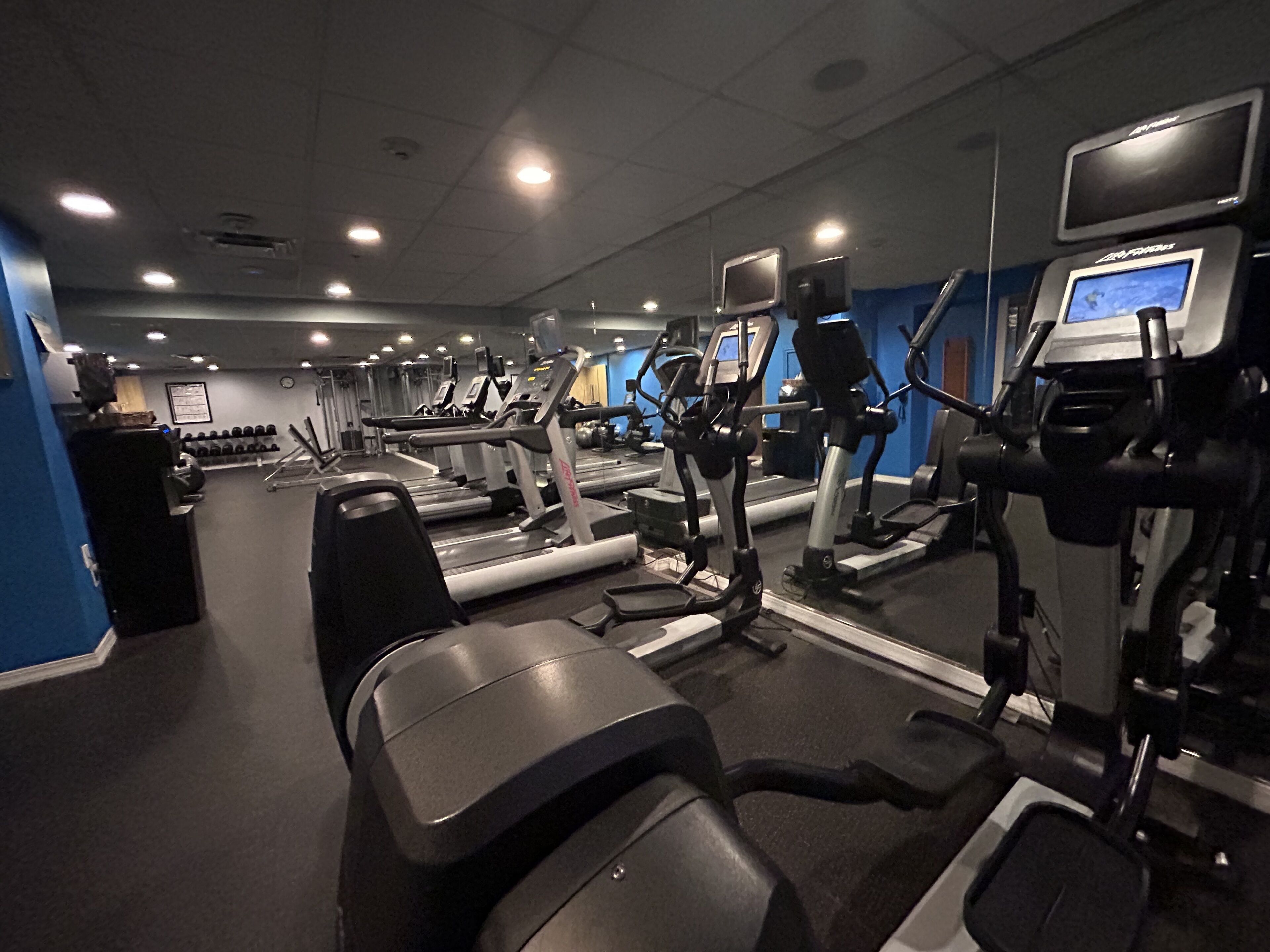 Un gimnasio con cintas de correr, elípticas y bancos de pesas.