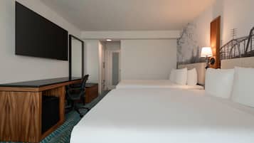 A hotel room with a large bed, a desk with a computer, a chair, and a wall-mounted TV.