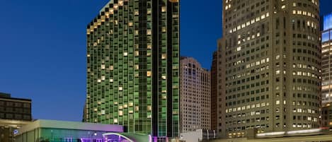 A modern hotel with a prominent glass facade and a unique purple-lit entrance.