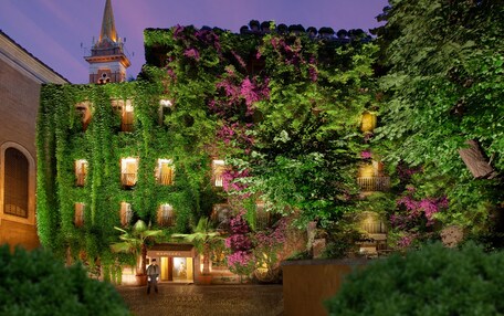 A hotel with ivy-covered walls, a prominent tower, and a well-lit entrance.