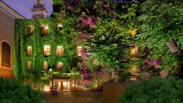 A hotel with ivy-covered walls, a prominent tower, and a well-lit entrance. - Hotel Raphaël – Relais & Châteaux (Rome)