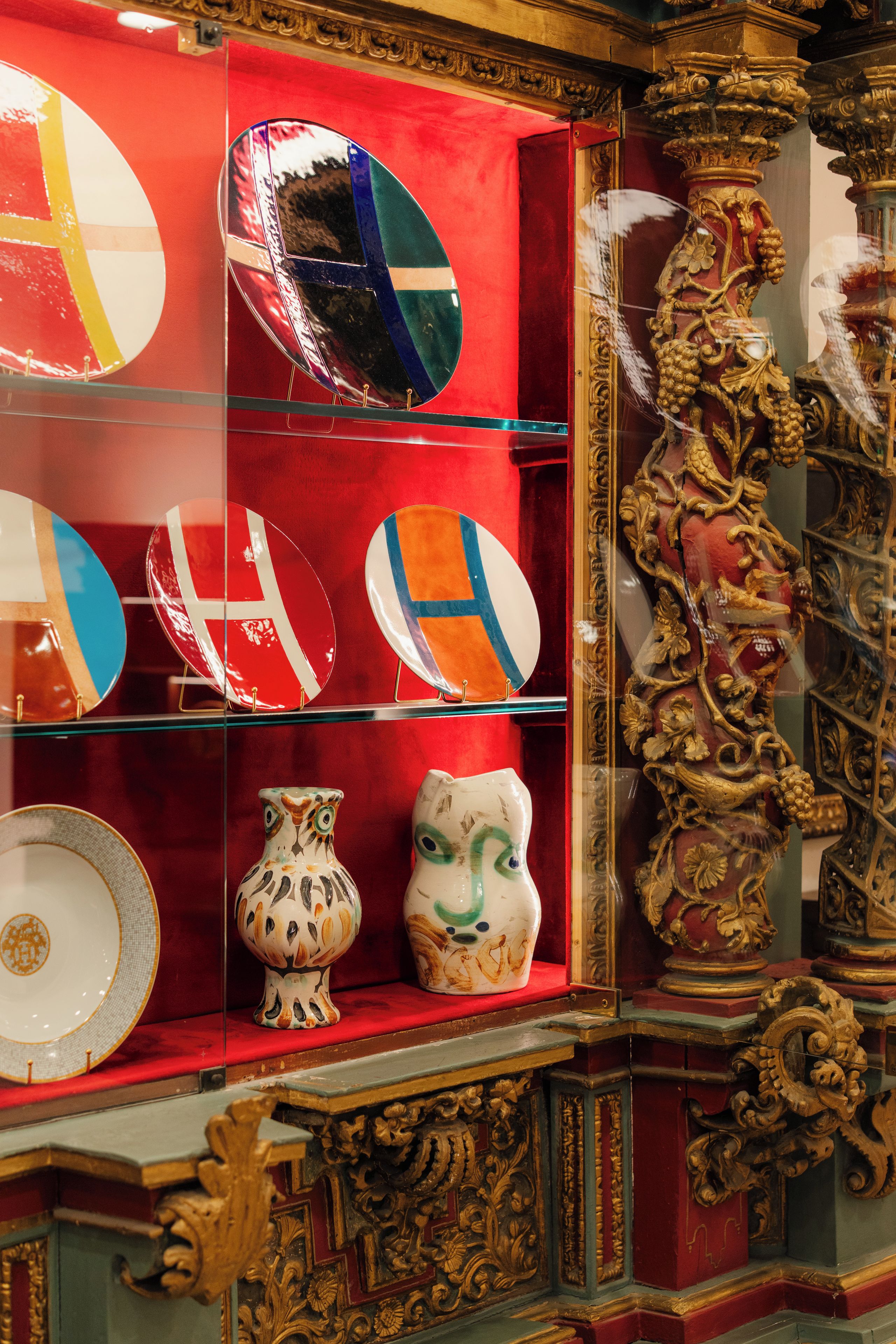 Une collection d’assiettes décoratives et une chouette en céramique sont exposées sur une étagère.