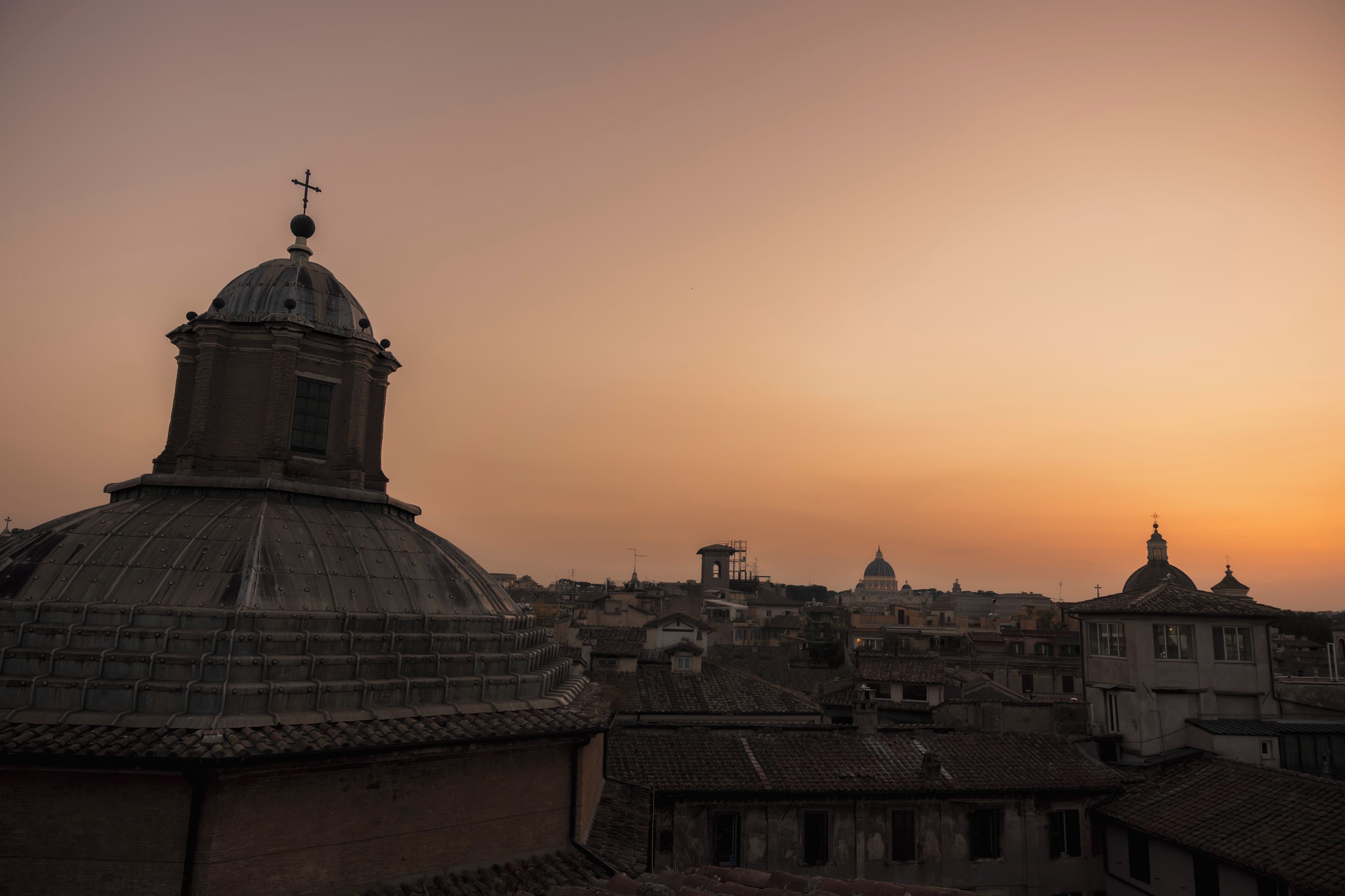 Un edificio storico con una cupola e una croce, circondato da architettura tradizionale.