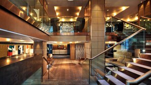 Un moderno vestíbulo de hotel con una escalera de cristal, una araña y un mostrador de recepción.
