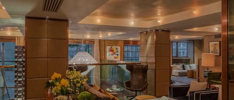Un interior moderno con una zona de estar, una mesa de vidrio y un candelabro decorativo.