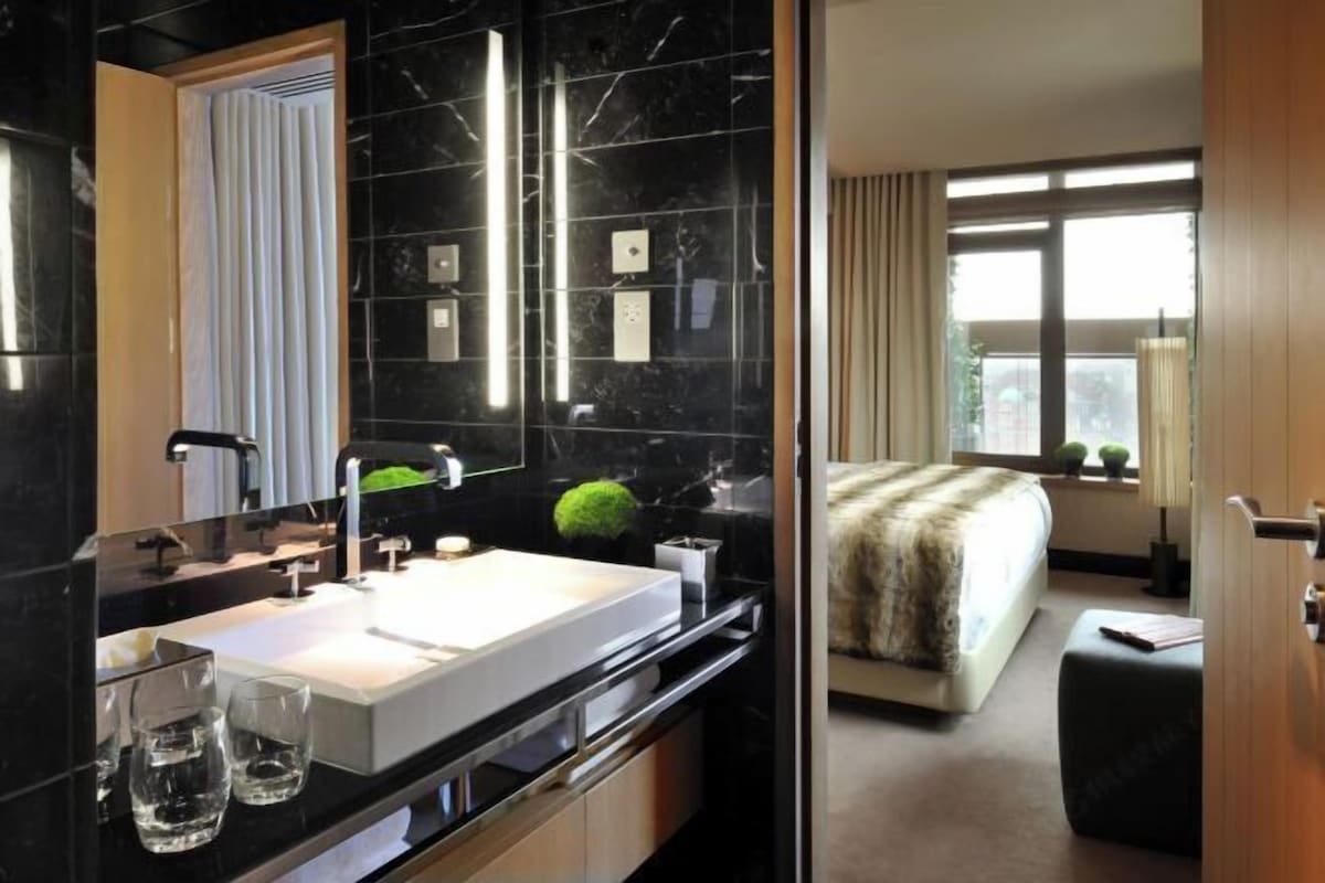 A modern bathroom with a large mirror, a white sink, and a black countertop.