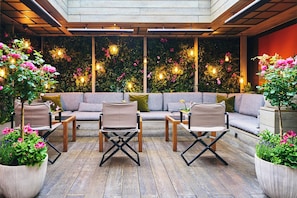 An outdoor seating area with a wooden deck, cushioned sofas, and foldable chairs.