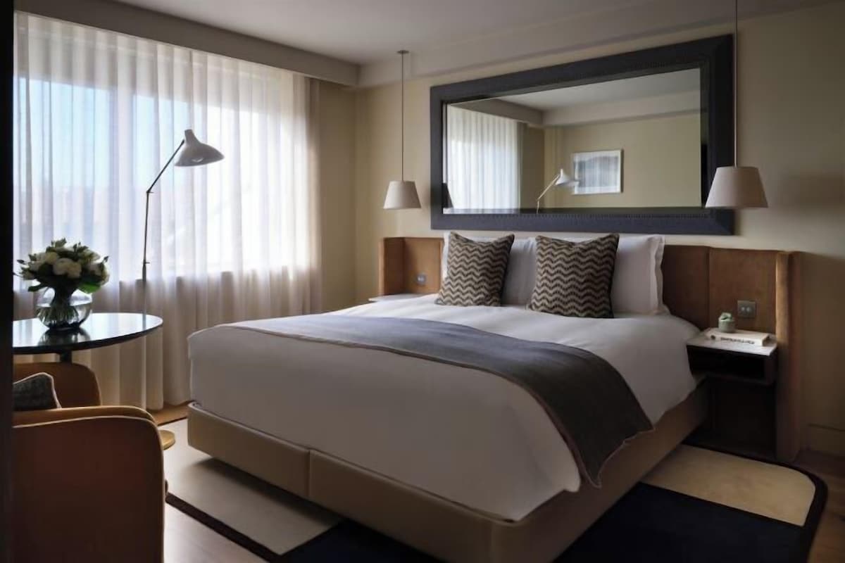 A hotel room with a large bed, bedside tables, a desk, and a chair.