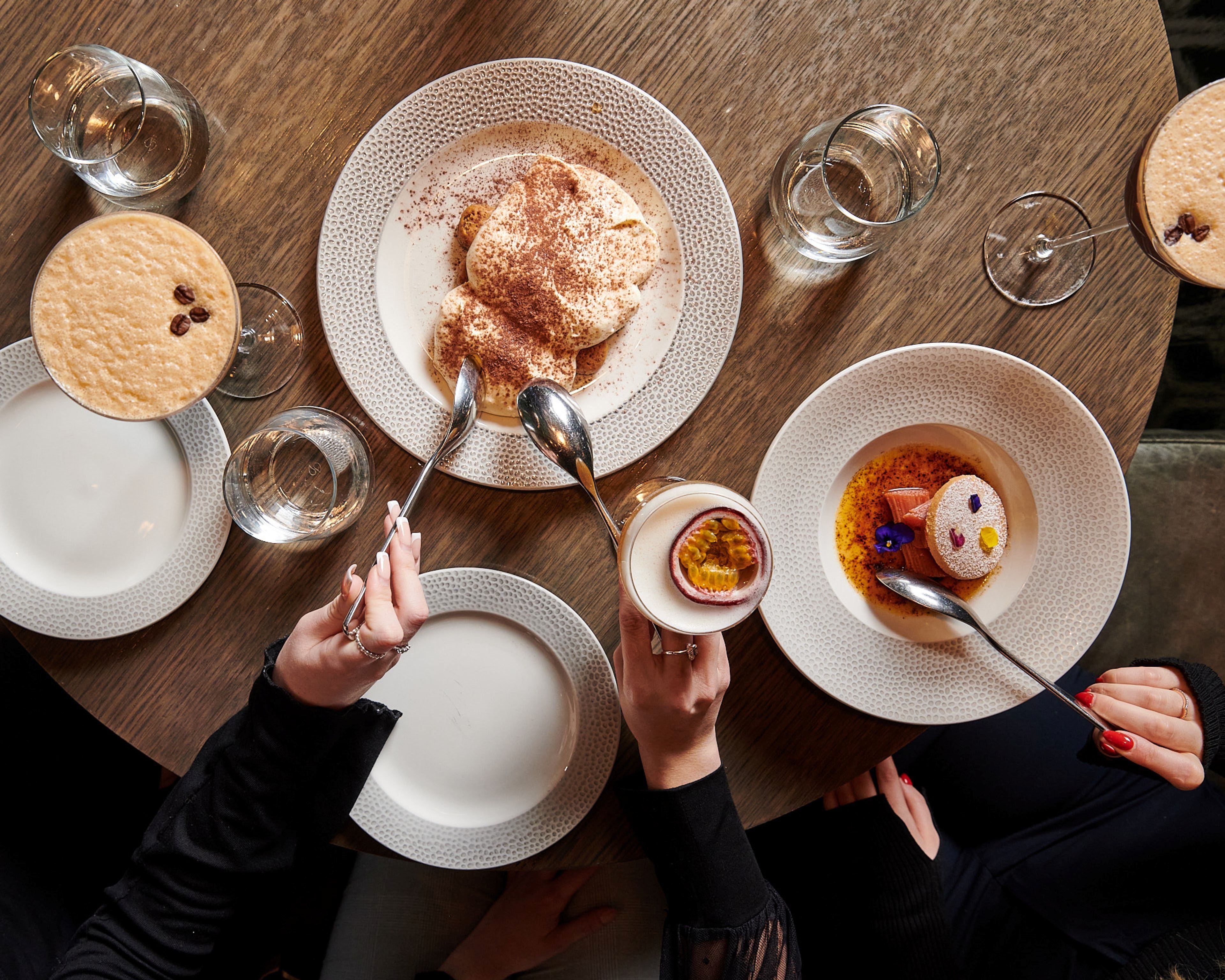A table set with plates of food, glasses of water, and a dessert.