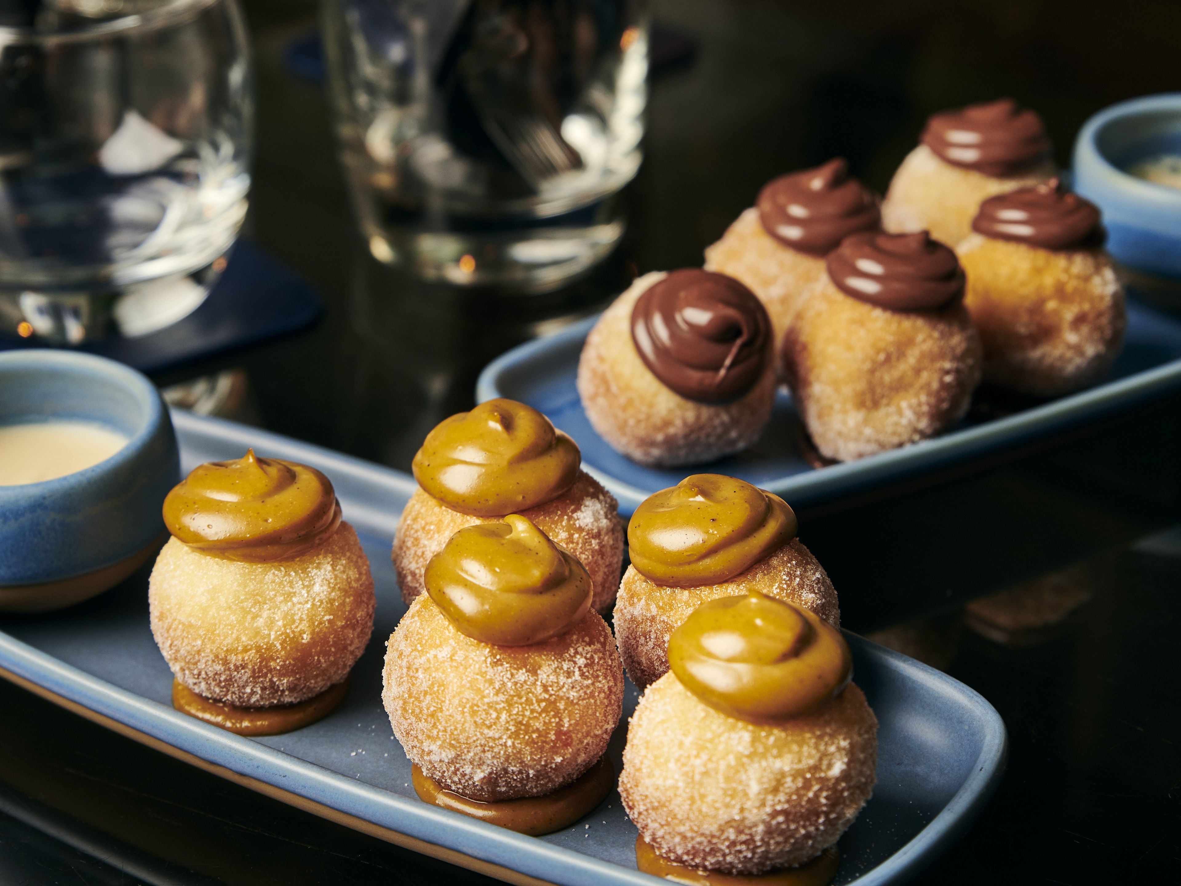 Ein Dessertteller mit mit Zucker bestreuten Gebäckstücken, verziert mit Karamell und Schokolade.