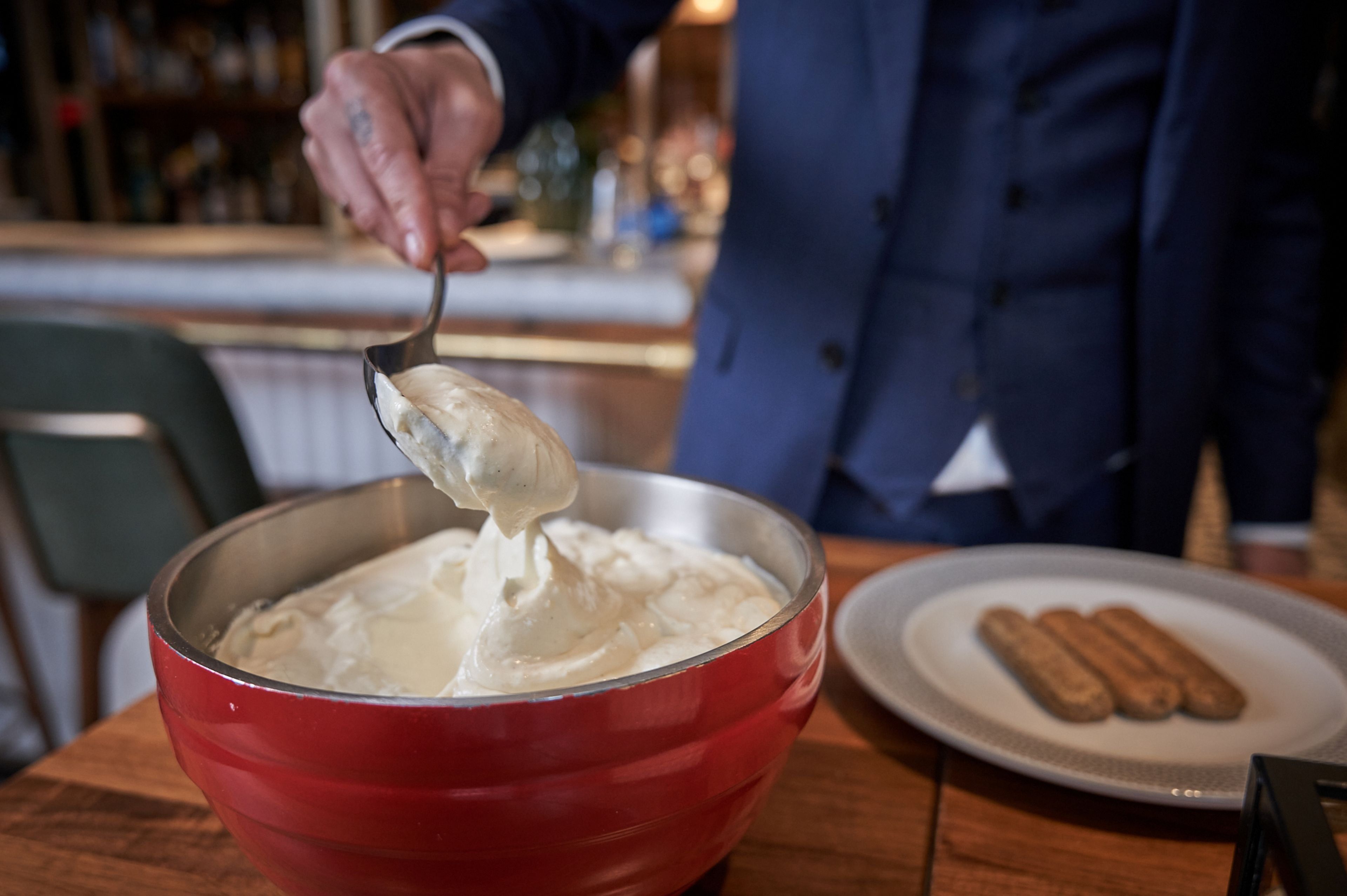 A person scooping a creamy substance from a red bowl.