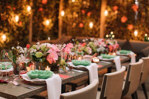 A dining table set with plates, glasses, and flowers, surrounded by chairs. - The Hari (London)
