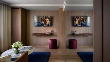 A modern hotel room with a wooden floor, a marble table, a vase with flowers, and two red stools.