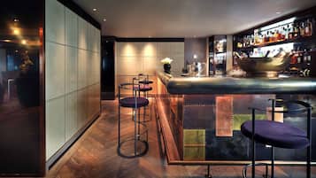 Eine moderne Bar mit einer Bar, Hockern und einem gut sortierten Spirituosenregal.