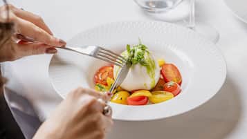 A person cutting a salad with a fork on a white plate.