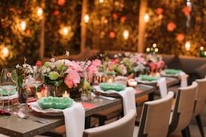 Una mesa de comedor lista, con platos, cubiertos y centros de mesa florales.
