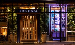 Entrada de un hotel con un cartel que dice 'THE HARI' y una exhibición de obras de arte enmarcadas.