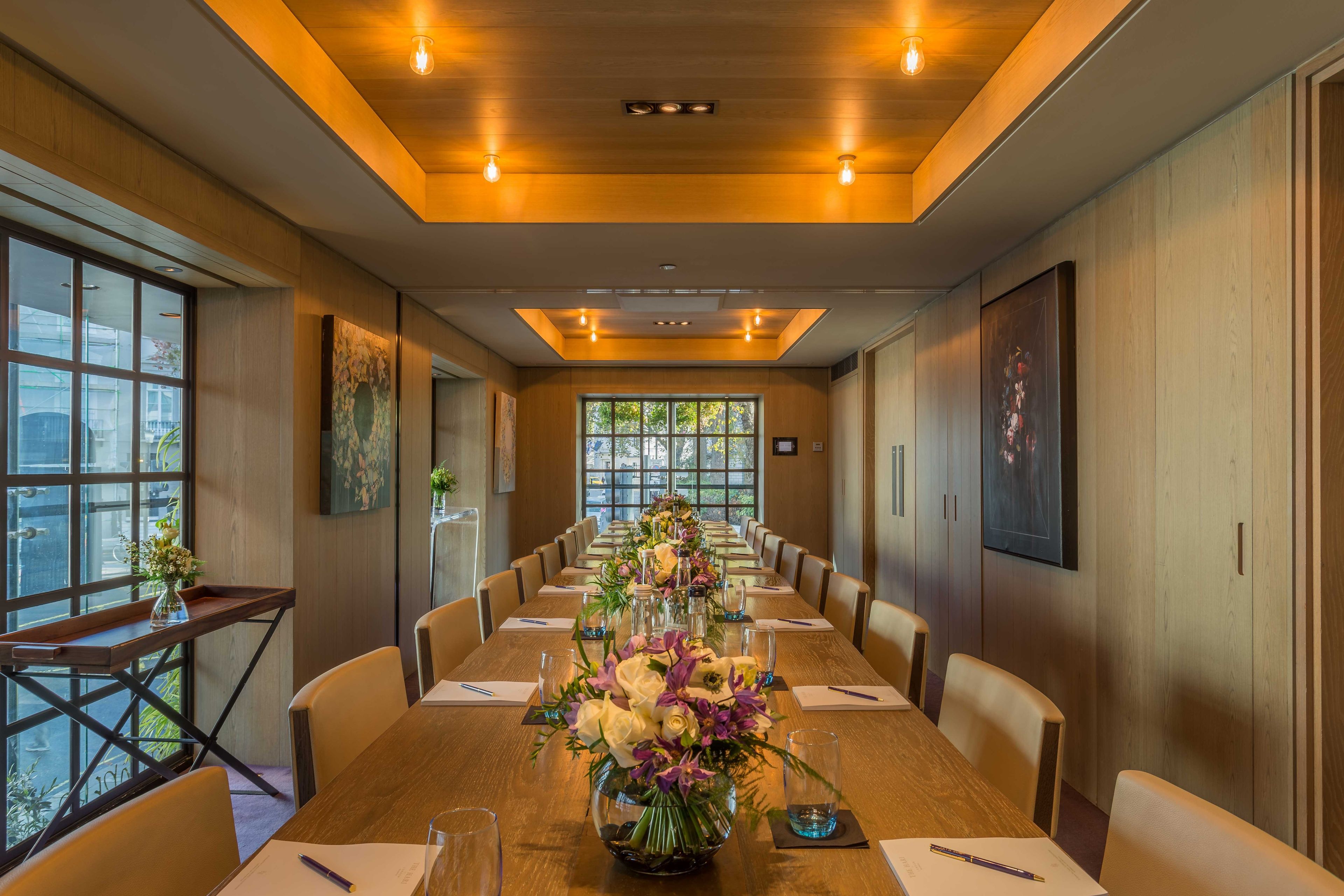 A conference room with a long table, chairs, and a floral centerpiece.