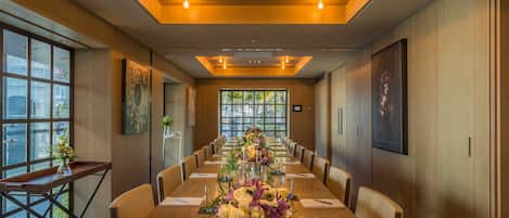 Un salón de conferencias con una larga mesa, sillas y un centro de mesa floral.