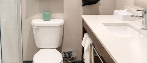 A modern bathroom with a toilet, a sink, and a trash bin.