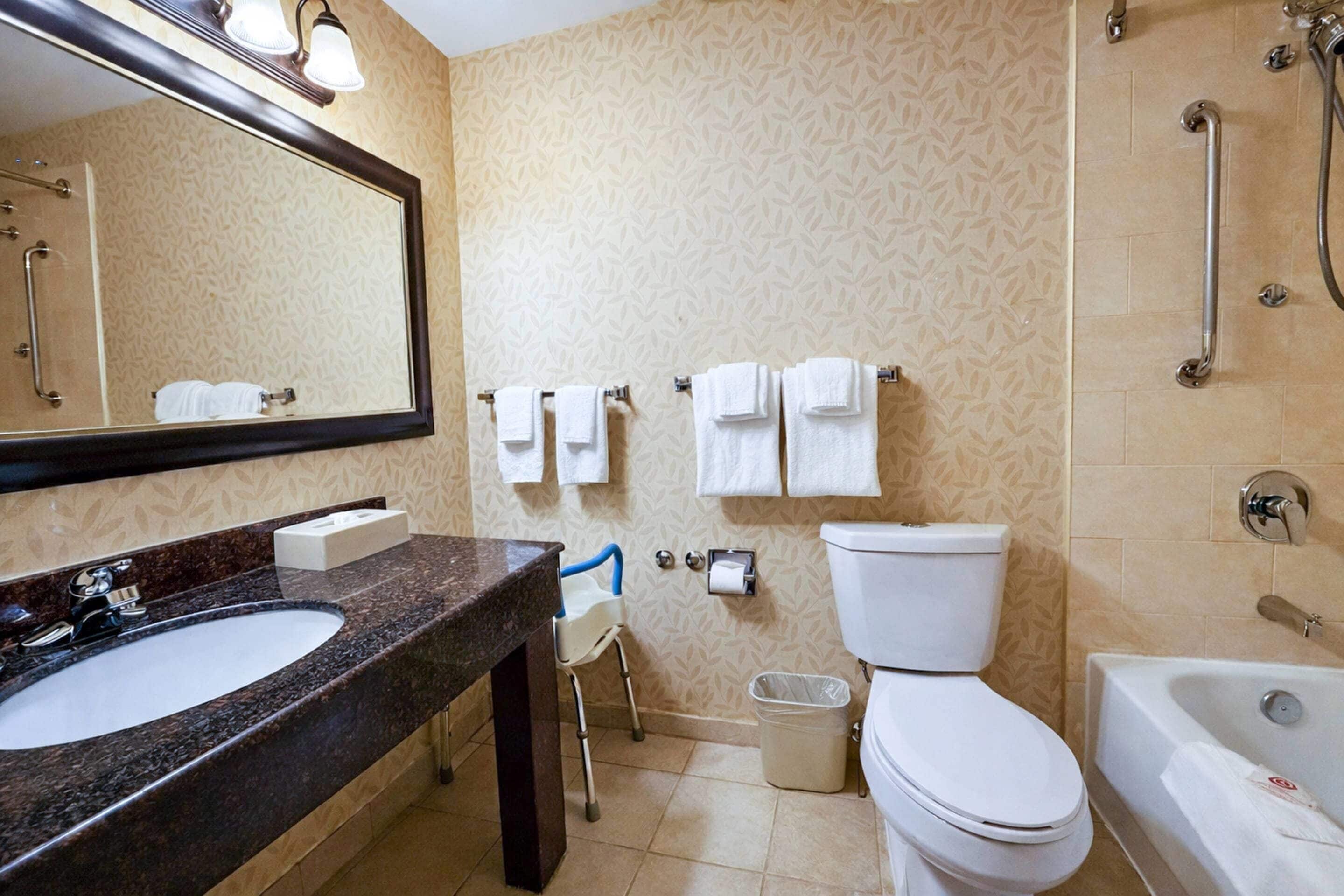 A bathroom with a sink, toilet, and bathtub, a mirror, and a shower area.