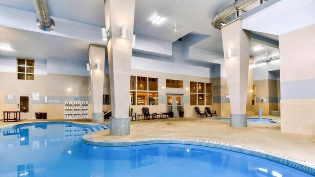 Una piscina interior con agua cristalina, rodeada de tumbonas y una zona de estar con mesas.