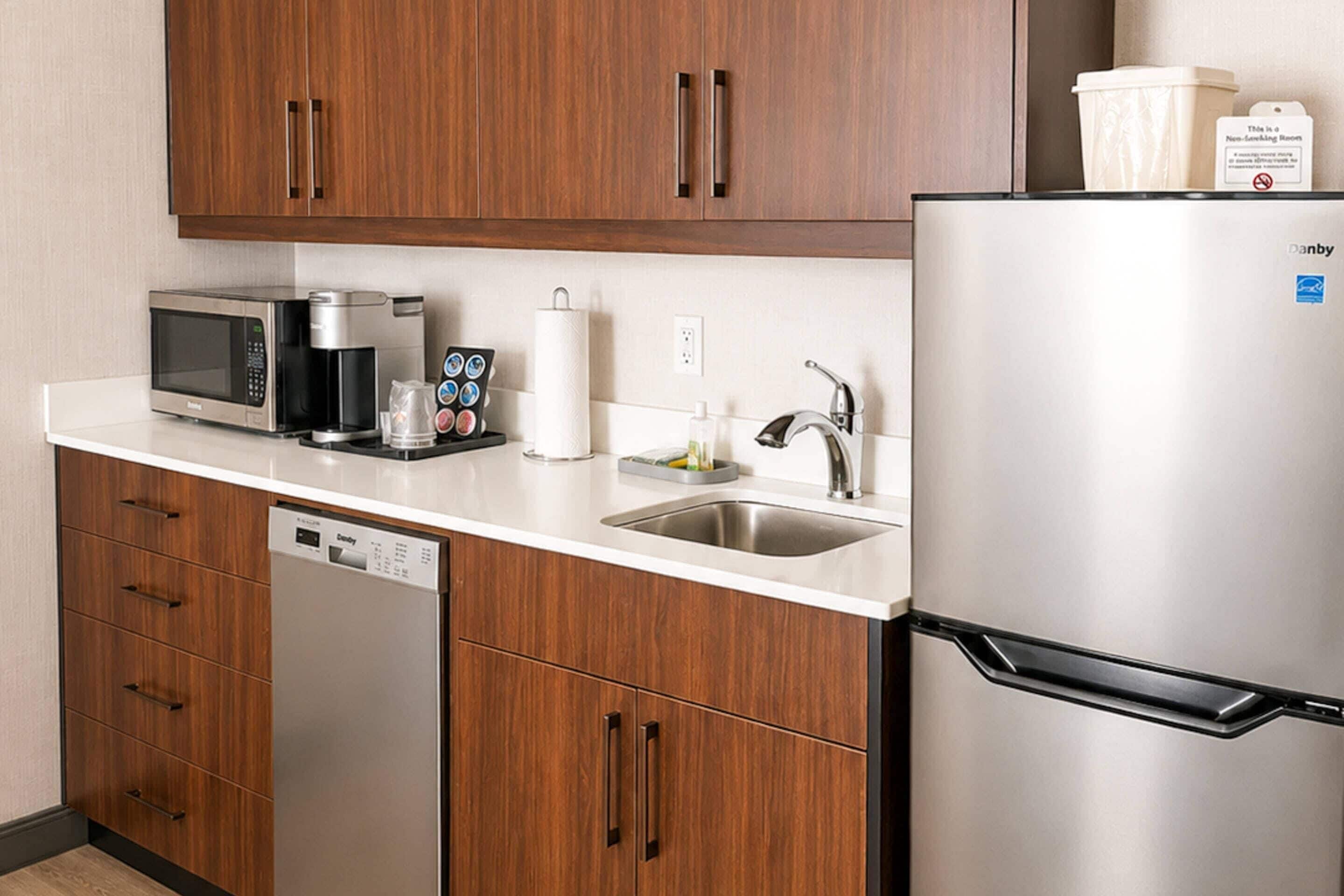 A modern kitchen with a stainless steel refrigerator, a microwave, a coffee maker, and a dishwasher.