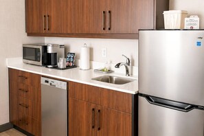Una cocina moderna con un refrigerador de acero inoxidable, un microondas, una cafetera y un lavavajillas.