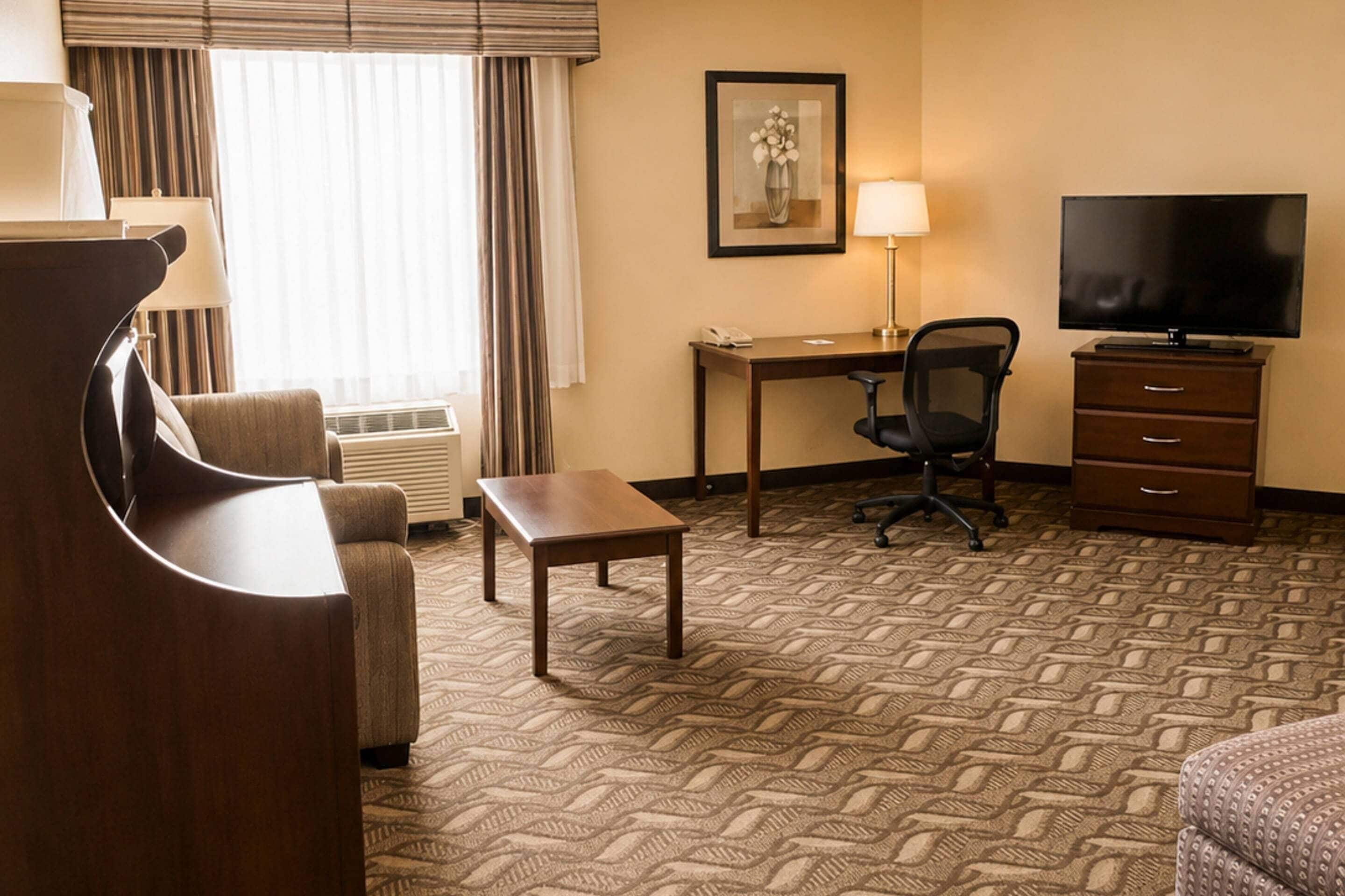 Una habitación de hotel con escritorio, silla, televisor y cama.