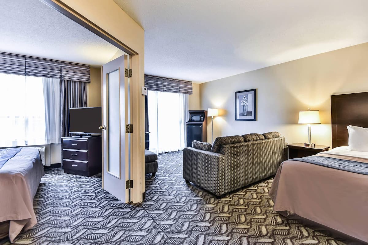 A hotel room with a bed, a sofa, a TV, a desk, and a lamp.