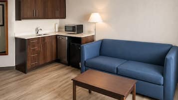A compact living space with a kitchenette, a blue sofa, and a wooden table.