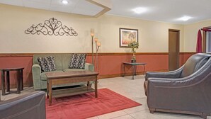 Un salon avec un canapé, des fauteuils, une table basse et un tapis rouge.