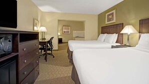 Une chambre d’hôtel avec deux lits, un bureau, une chaise, une télévision et une commode.