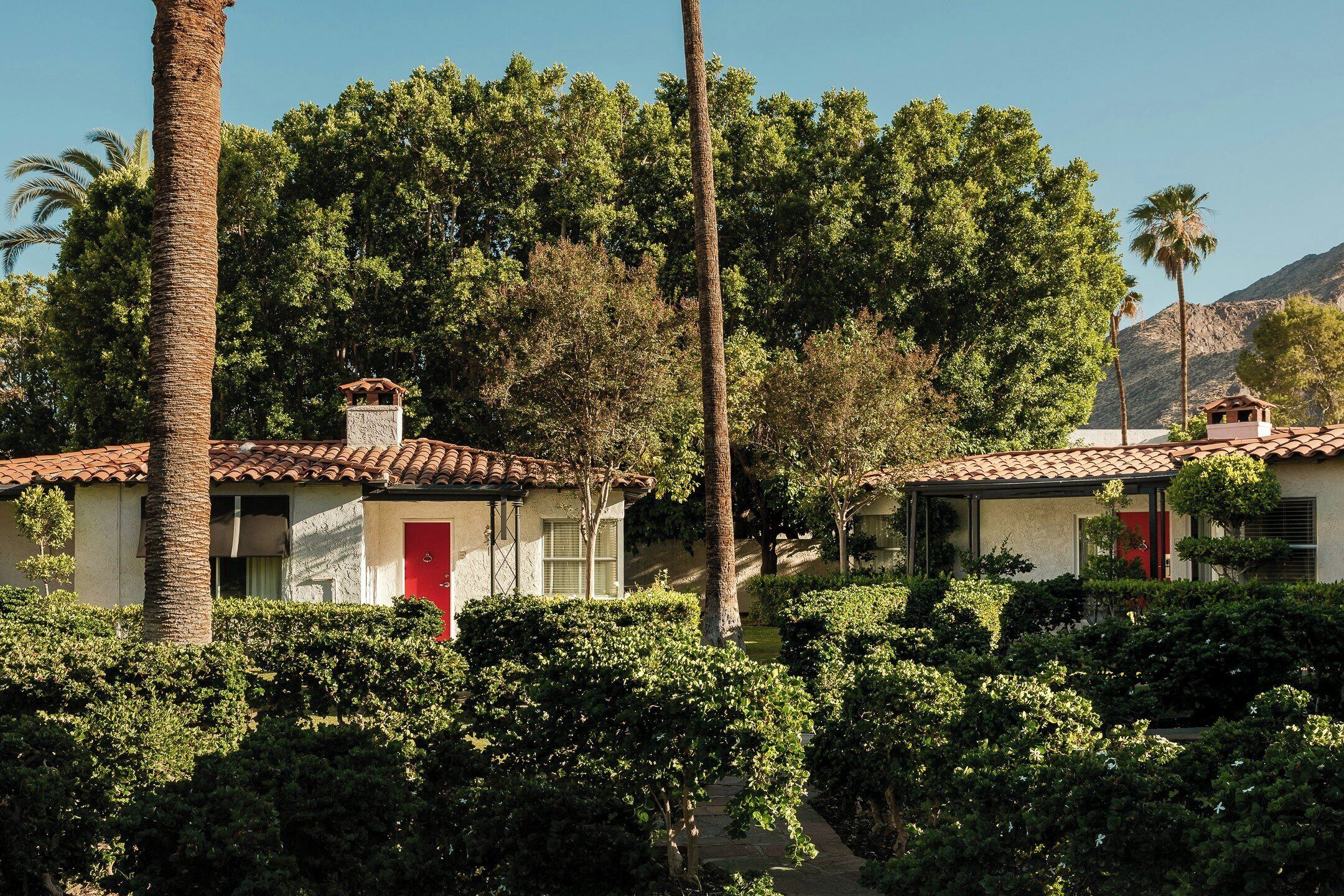 A residential area with two houses, each with a red door and a tiled roof.