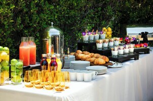 Un tavolo da buffet con diversi cibi, bevande e bicchieri.