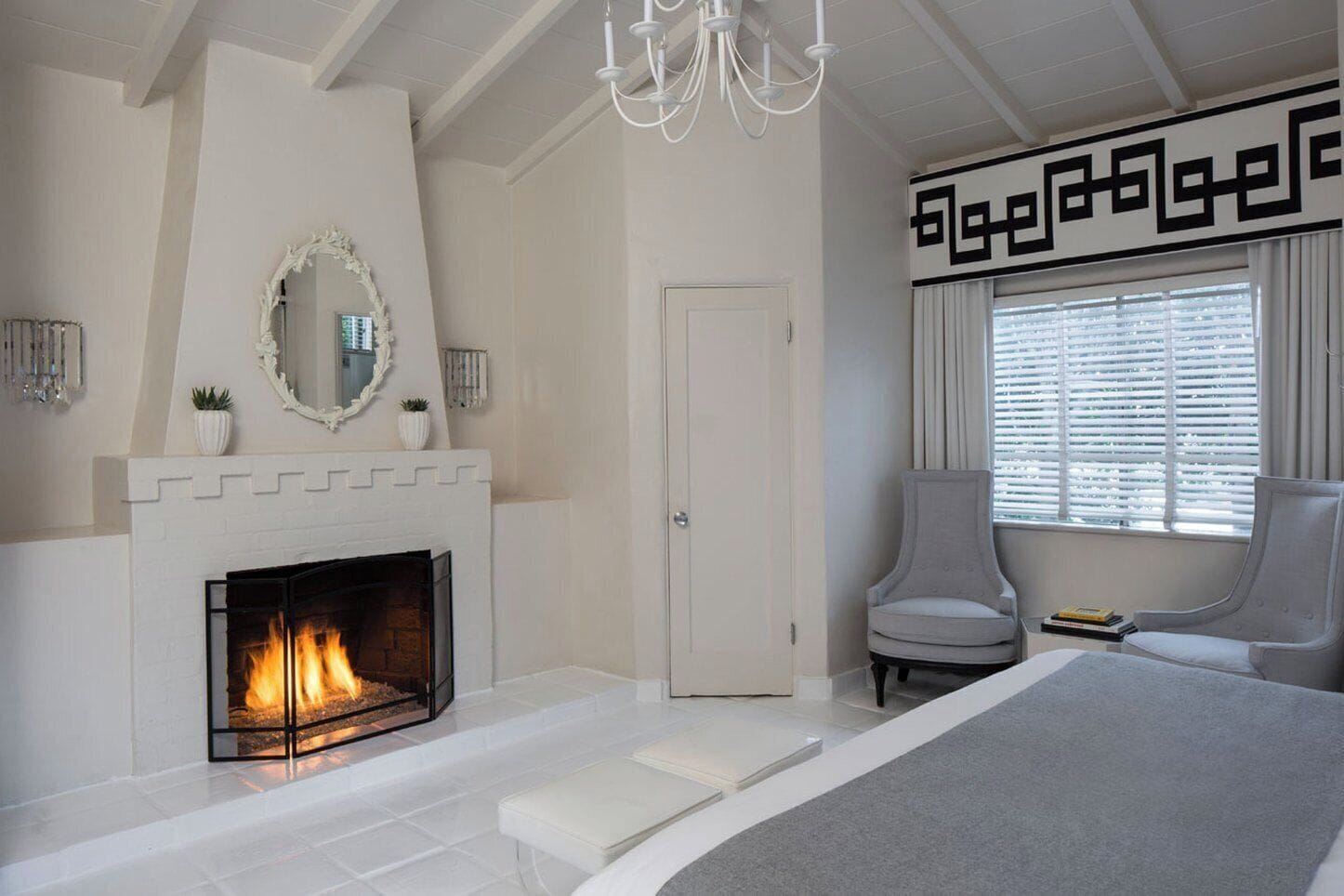 Un dormitorio moderno con chimenea, una cama grande, una silla y una ventana con persianas.