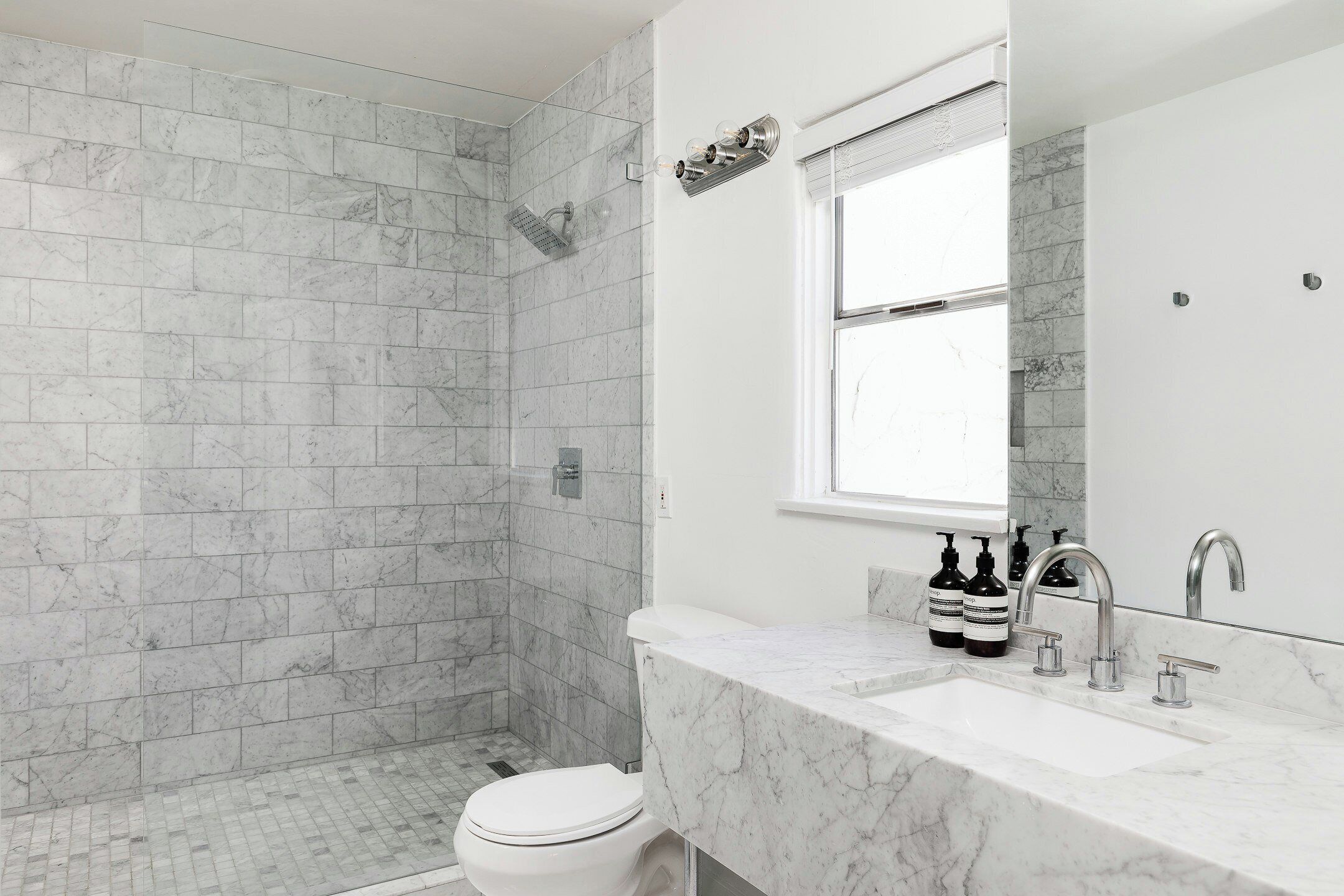 Un bagno con doccia, wc e lavabo con piano in marmo.