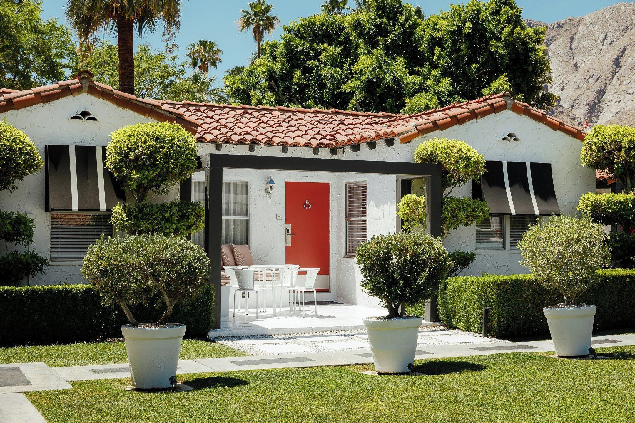Uma casa com porta vermelha, fachada branca e telhado em telhas.