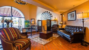 A cozy lounge area with leather sofas, a coffee table, and a large window offering a view of the street. - Best Western El Grande Inn (Clearlake)