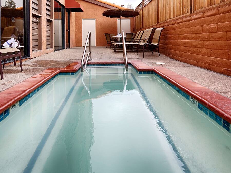 A rectangular pool with a tiled edge, surrounded by chairs and a table.