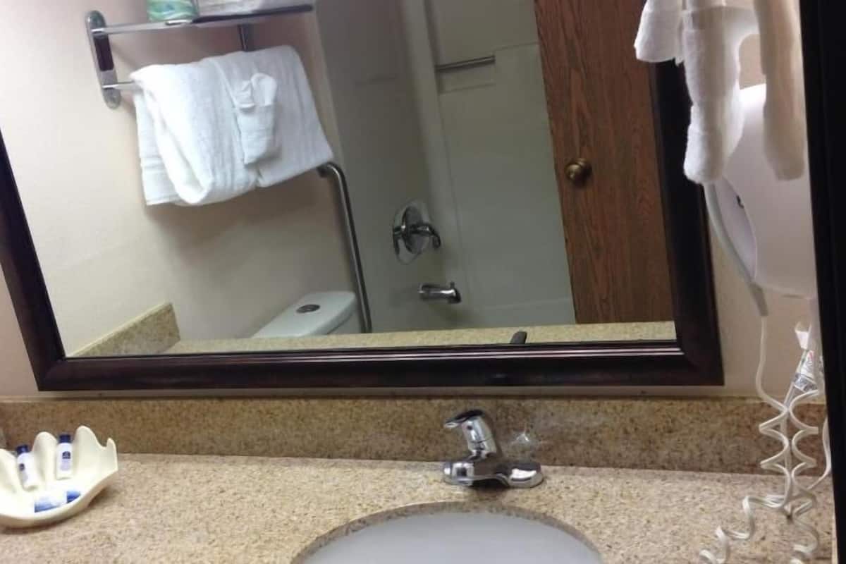 A bathroom with a sink, mirror, and towel rack.