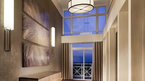 A hallway with a high ceiling, large windows, and a patterned carpet. - Hyatt Regency Long Island (Hauppauge)