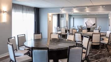 A conference room with a large round table surrounded by chairs, a carpeted floor, and a modern ceiling with track lighting.